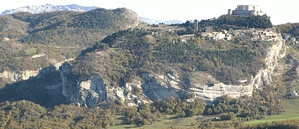 Le rupe di San Leo, punteggiata di lecci, precipite sul paesaggio agricolo digradante verso il Marecchia, e il Monte San Severino sullo sfondo di San Marino. Foto Stefano Bassi, archivio personale